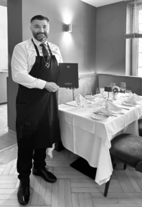 Rosario Morgana mit Speisekarte im Restaurant